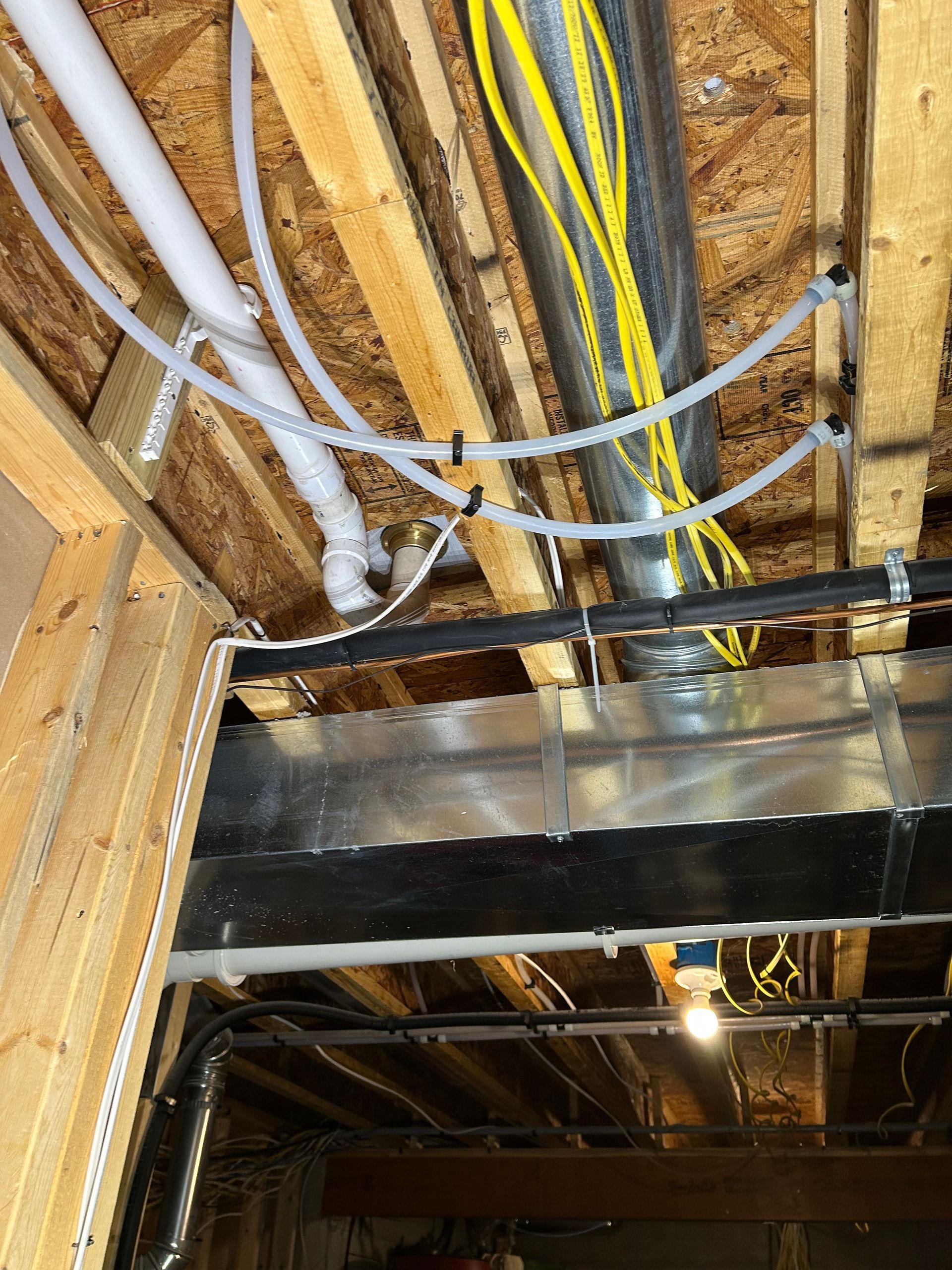 Exposed ceiling joists with bundled electrical wires, insulation, and ductwork in unfinished basement ceiling
