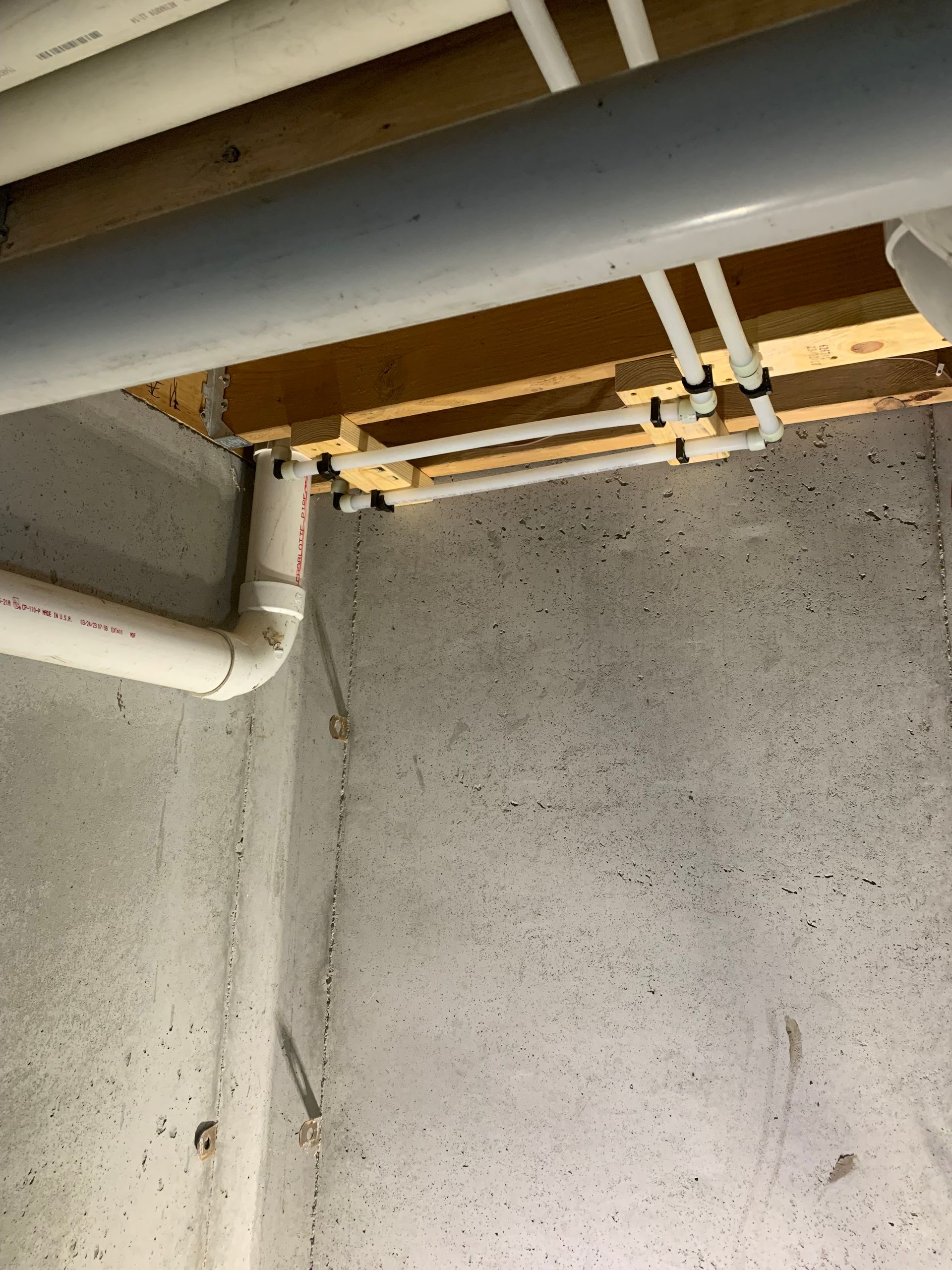 Two people inspecting plumbing under a sink with a toolbox in the foreground