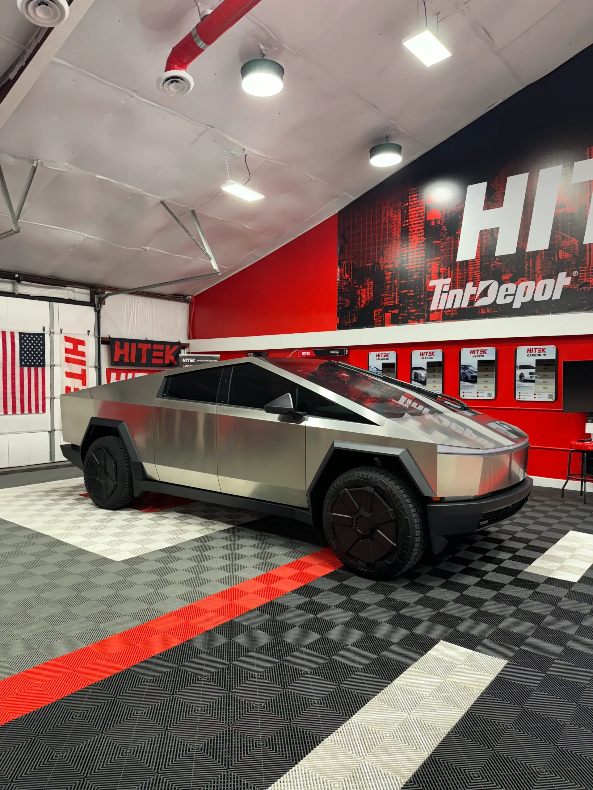 Tesla Cybertruck displayed in a garage with red accents and a HITe Depot sign.