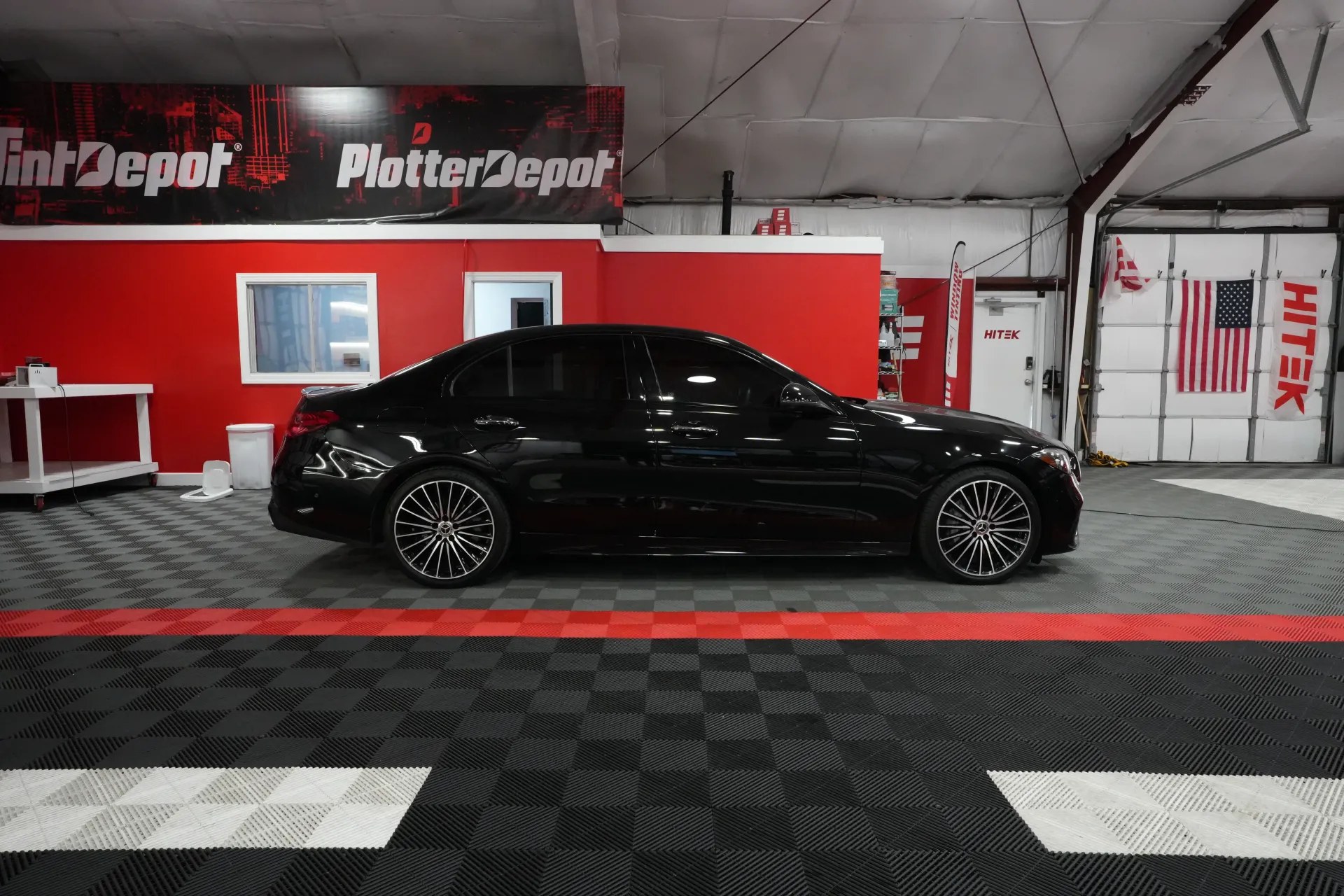 Black car inside shop with red accents, black wheels, shop name visible.