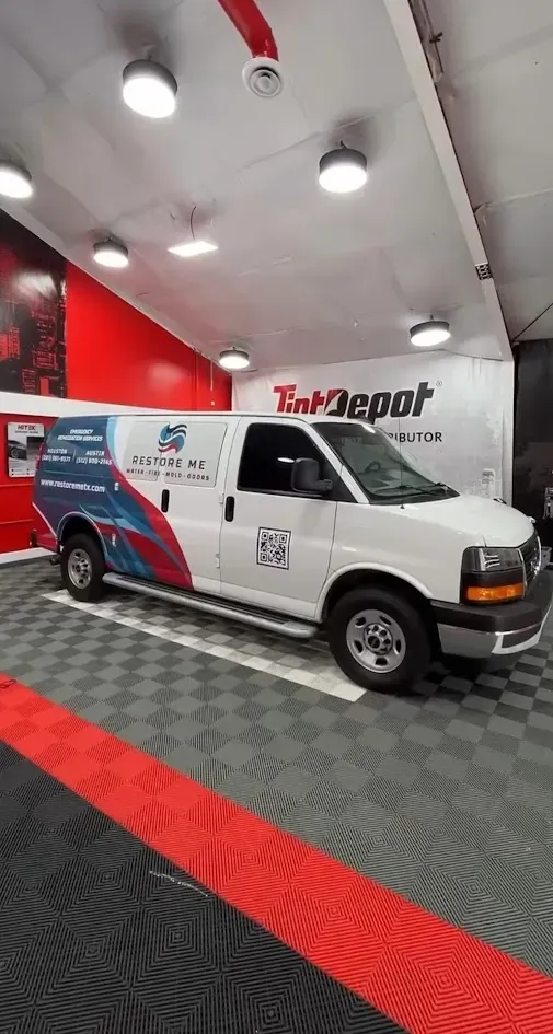 White service van with company logo parked inside a building with a checkered floor and red accents.