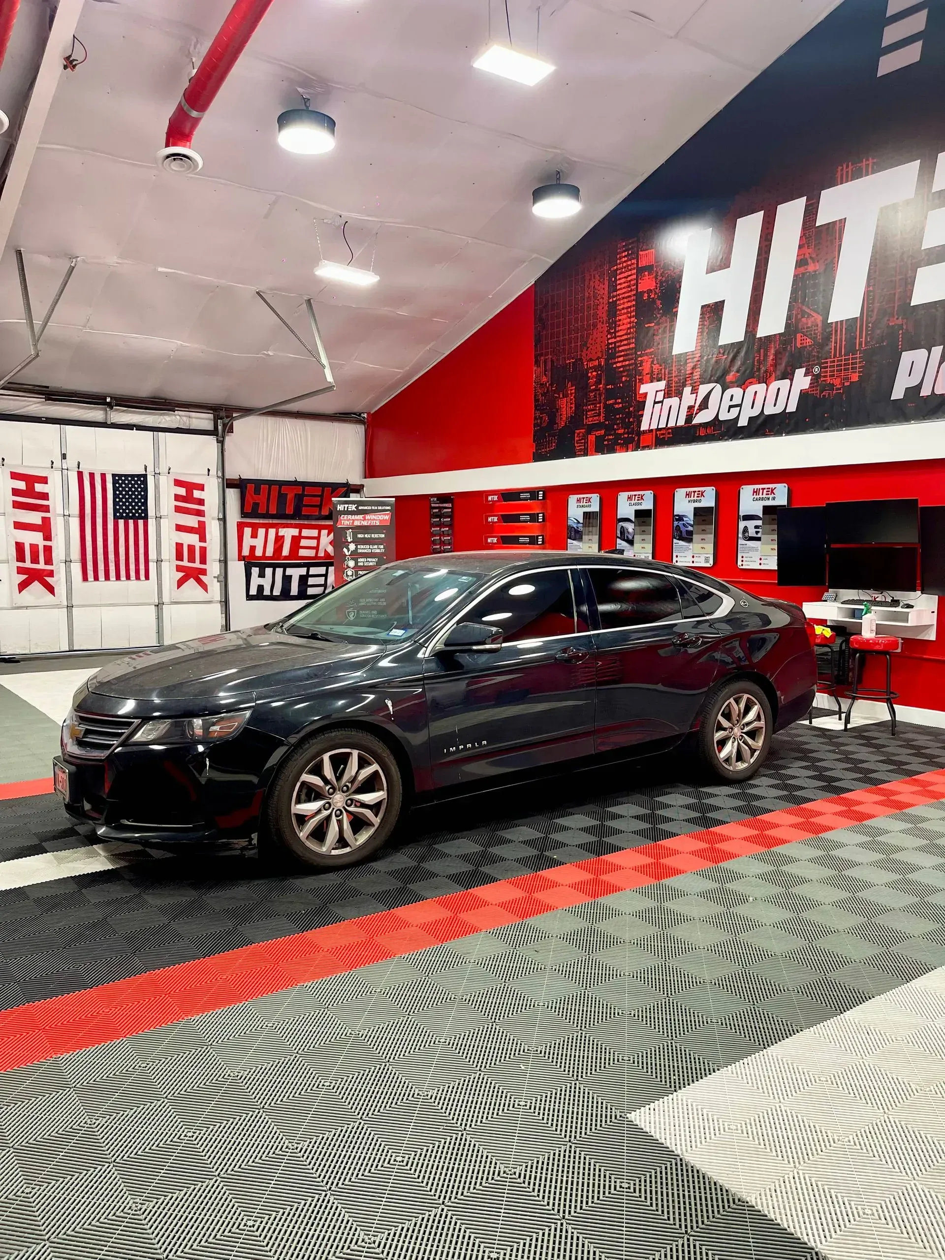 Black car inside auto shop with red and black accents.