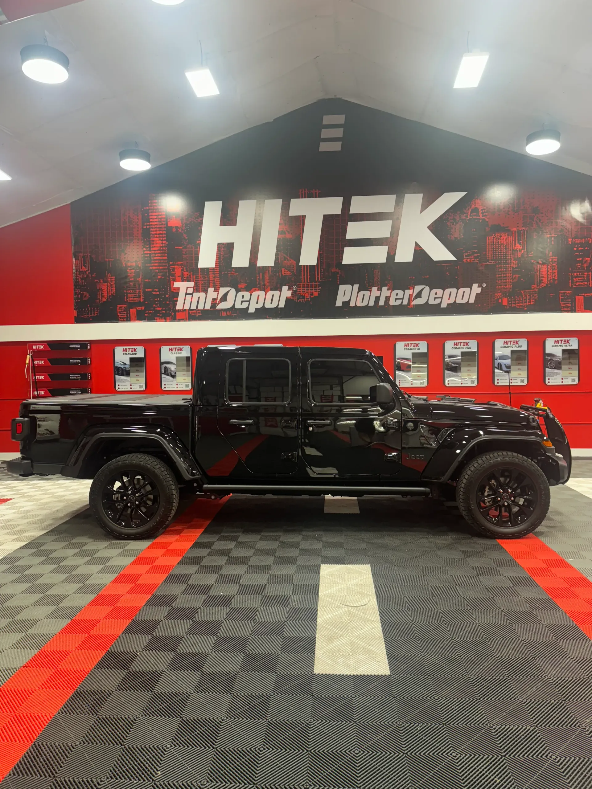 Black Jeep Gladiator truck parked inside a shop with 