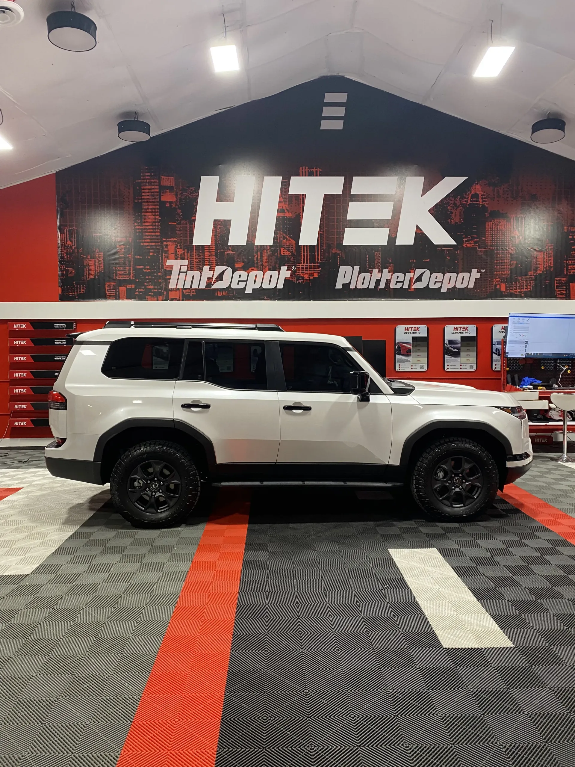 White SUV with black wheels inside a HiTek Tint Depot.