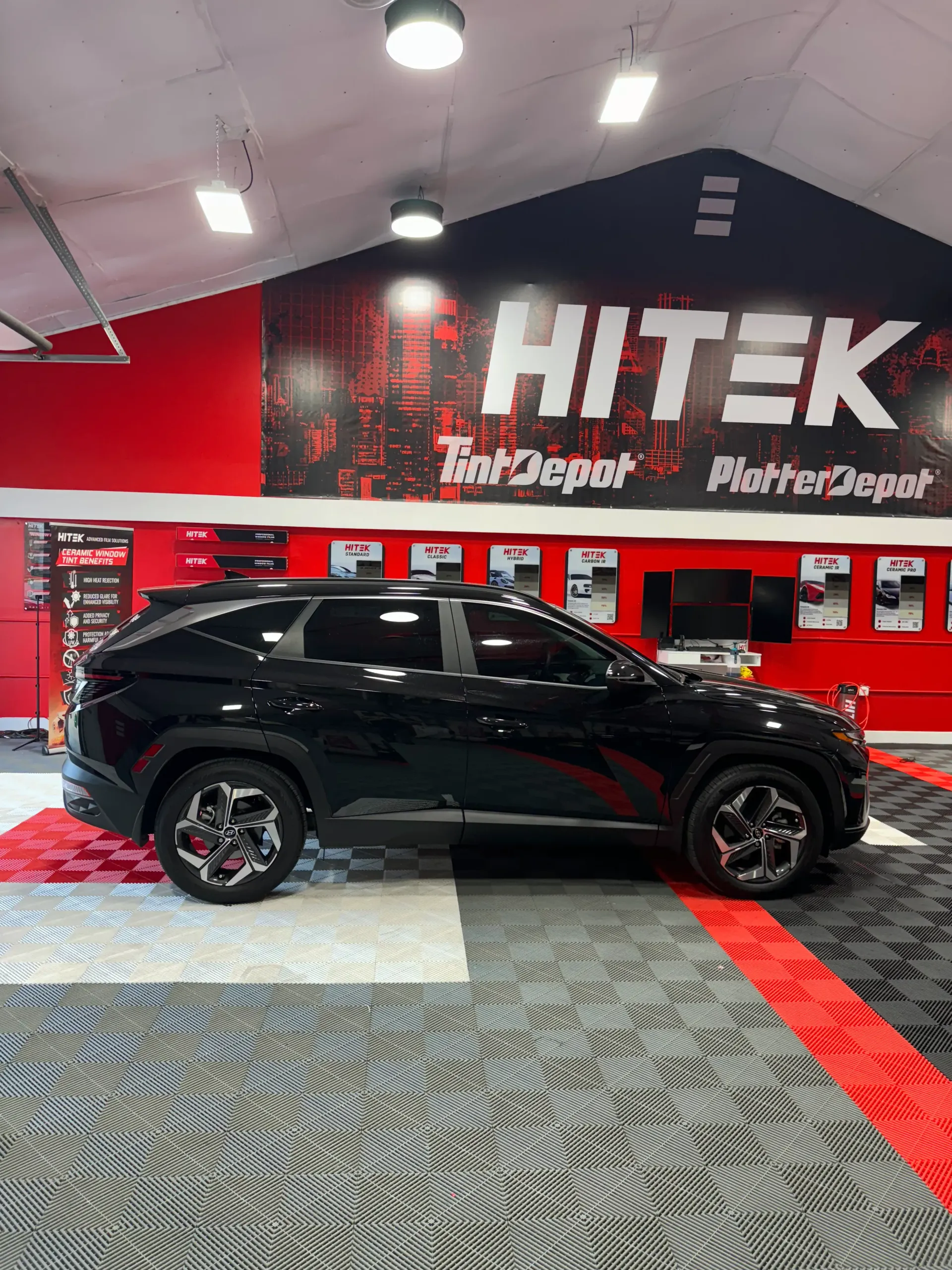 Black SUV parked in a shop with a red and black logo that says 
