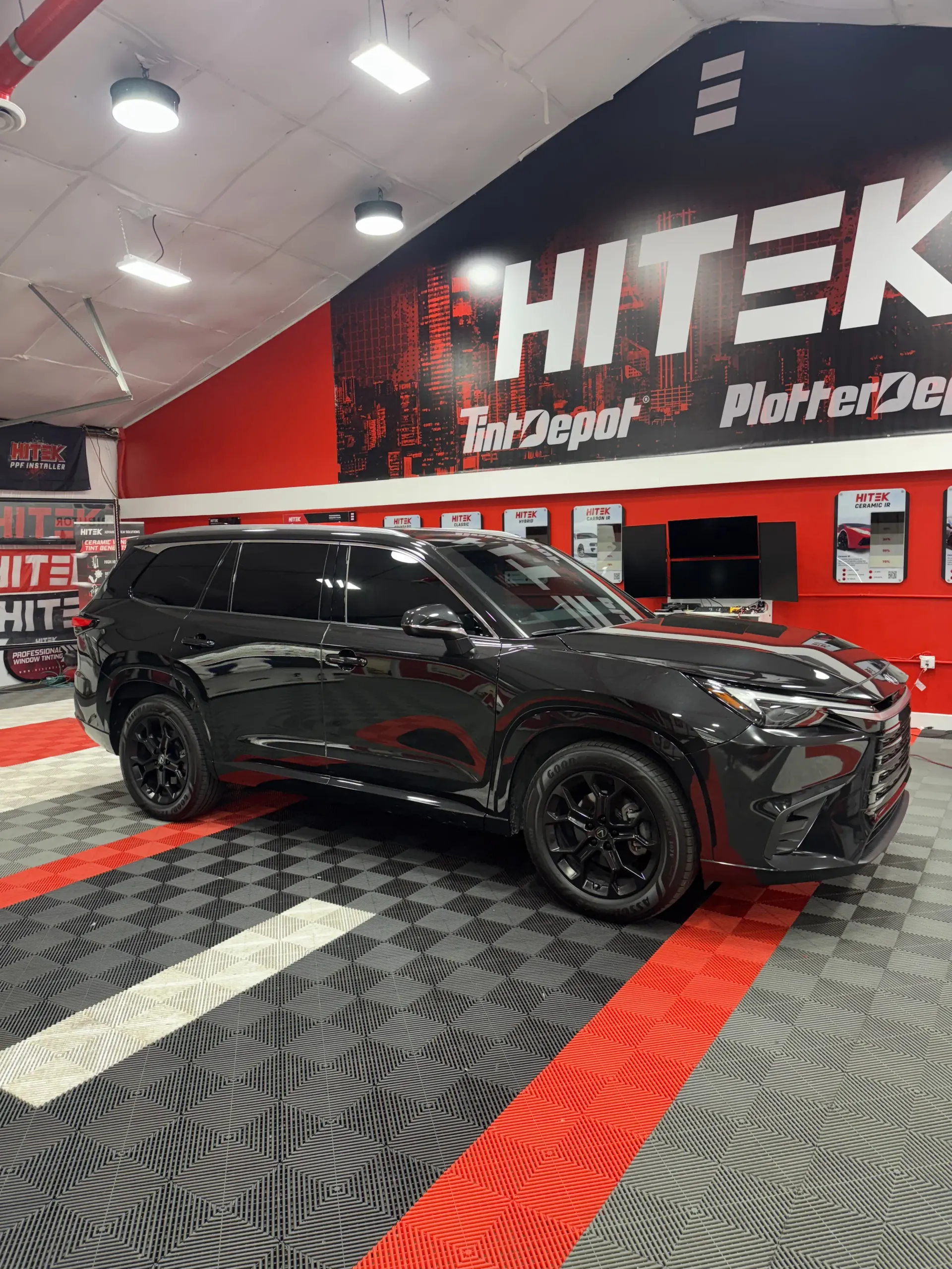 Black SUV parked inside a facility with red and white branding.