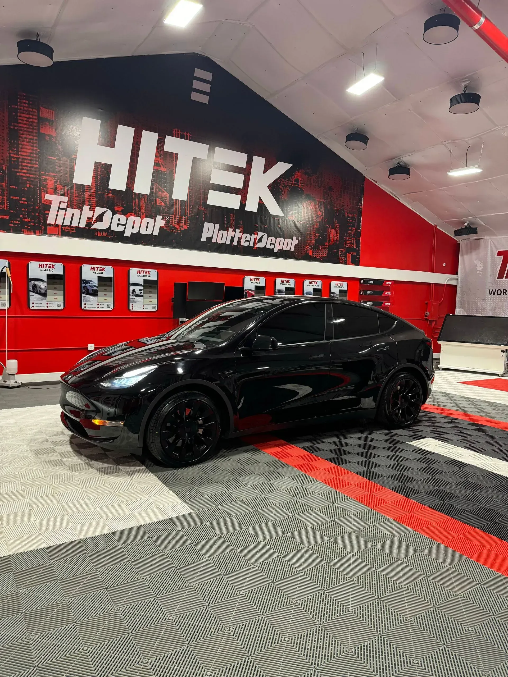 Black Ford Mustang Mach-E in a red and black shop with 