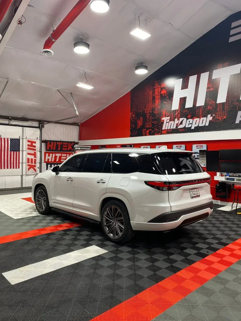 White SUV inside a shop with tinted windows, black and red flooring, and 