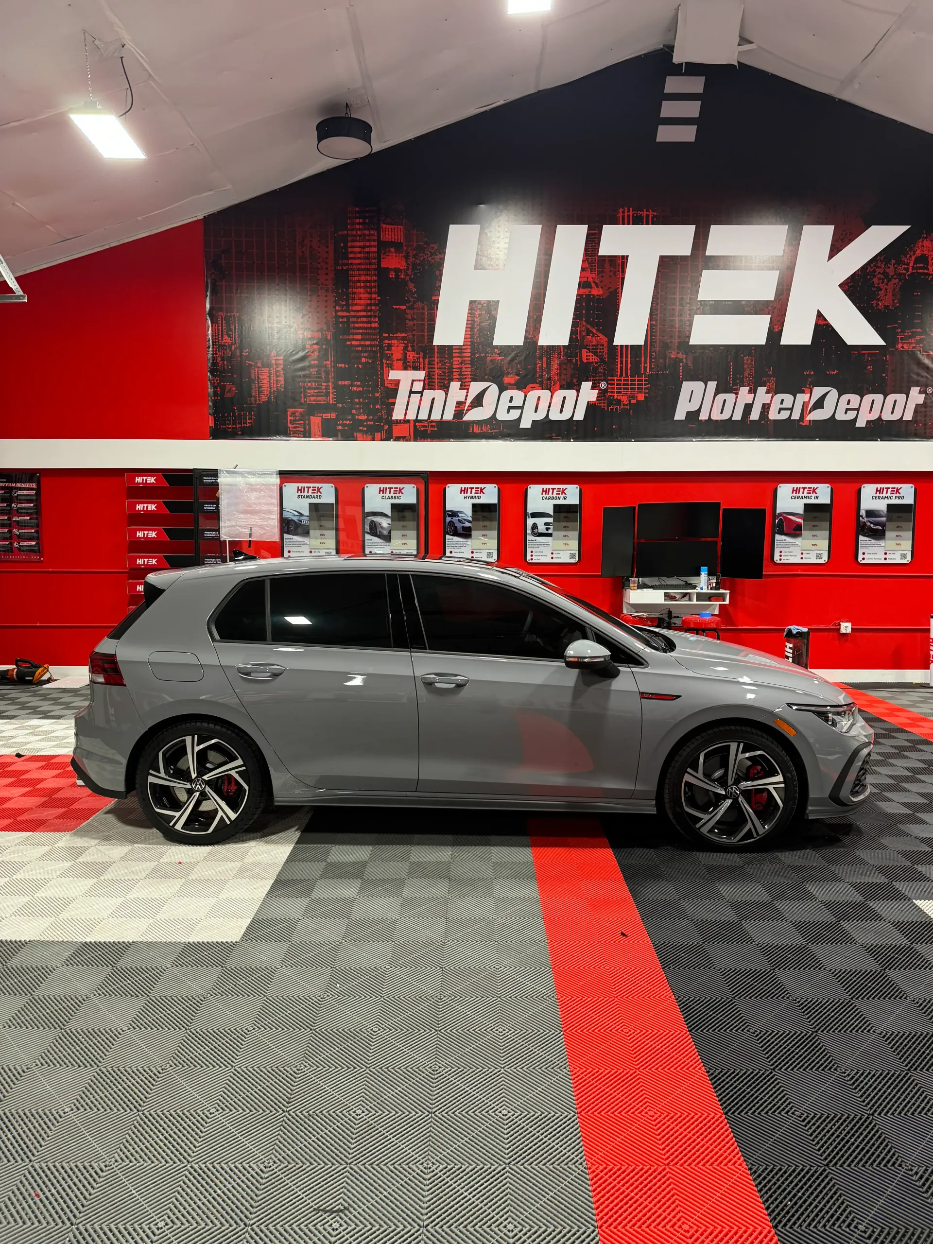 Gray Volkswagen Golf GTI parked in a red and black shop with 