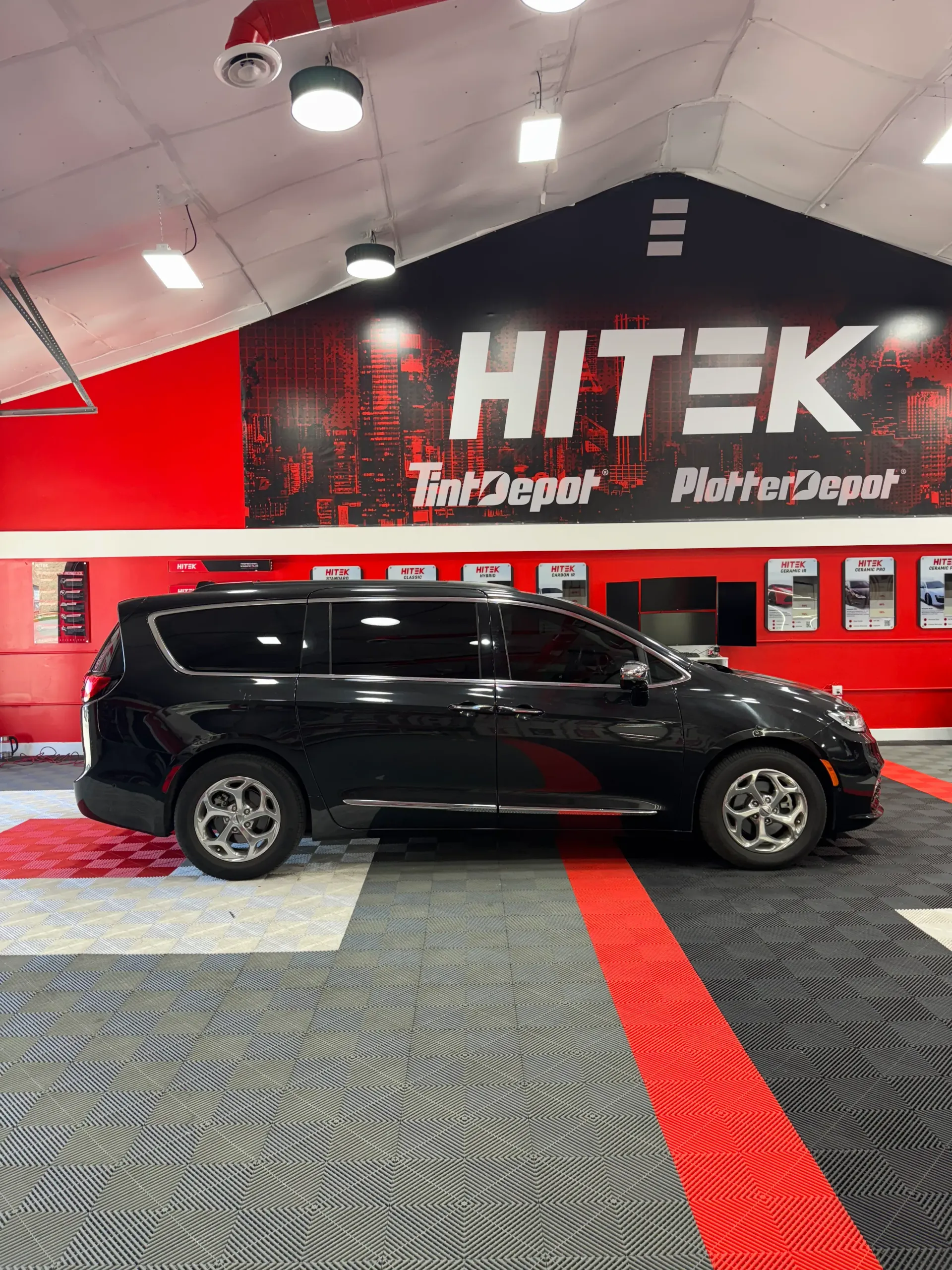 Black minivan parked inside a shop with a red and black logo 