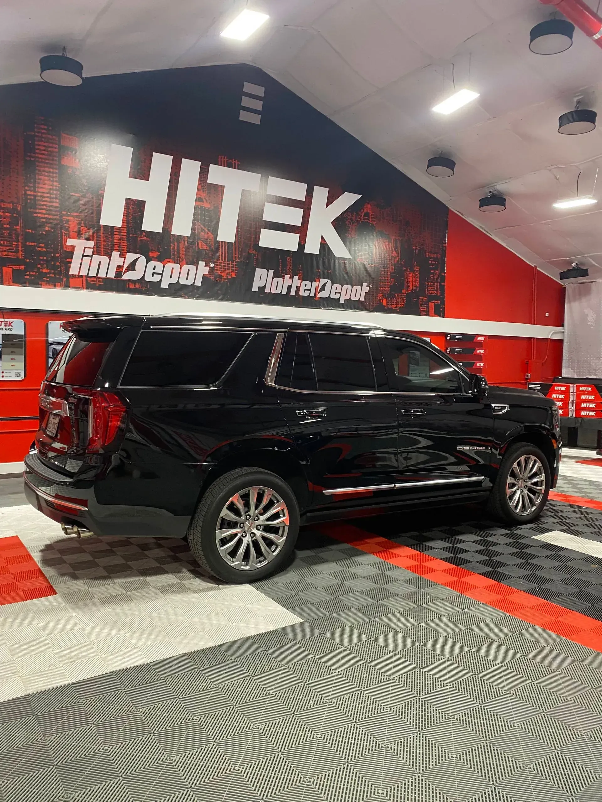 Black SUV parked in a Hitek Tool Depot shop with red and black accents.