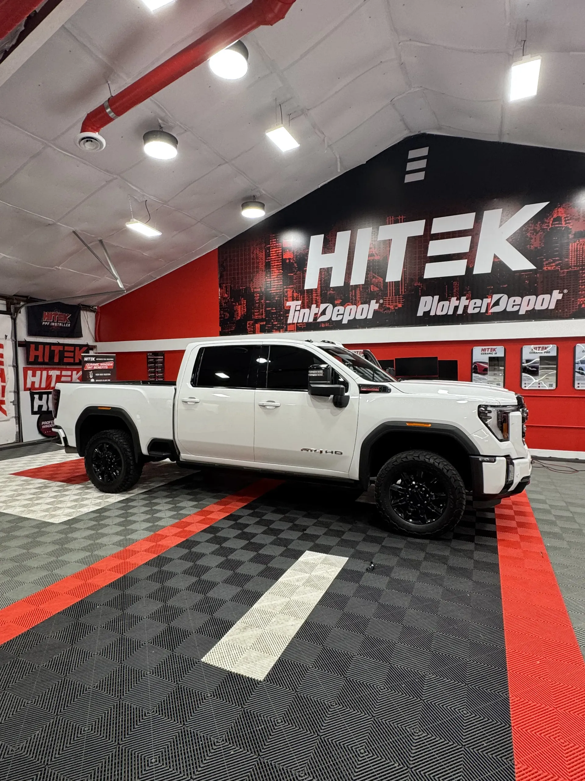 White GMC truck with black wheels, parked inside a garage with a Hitek sign.