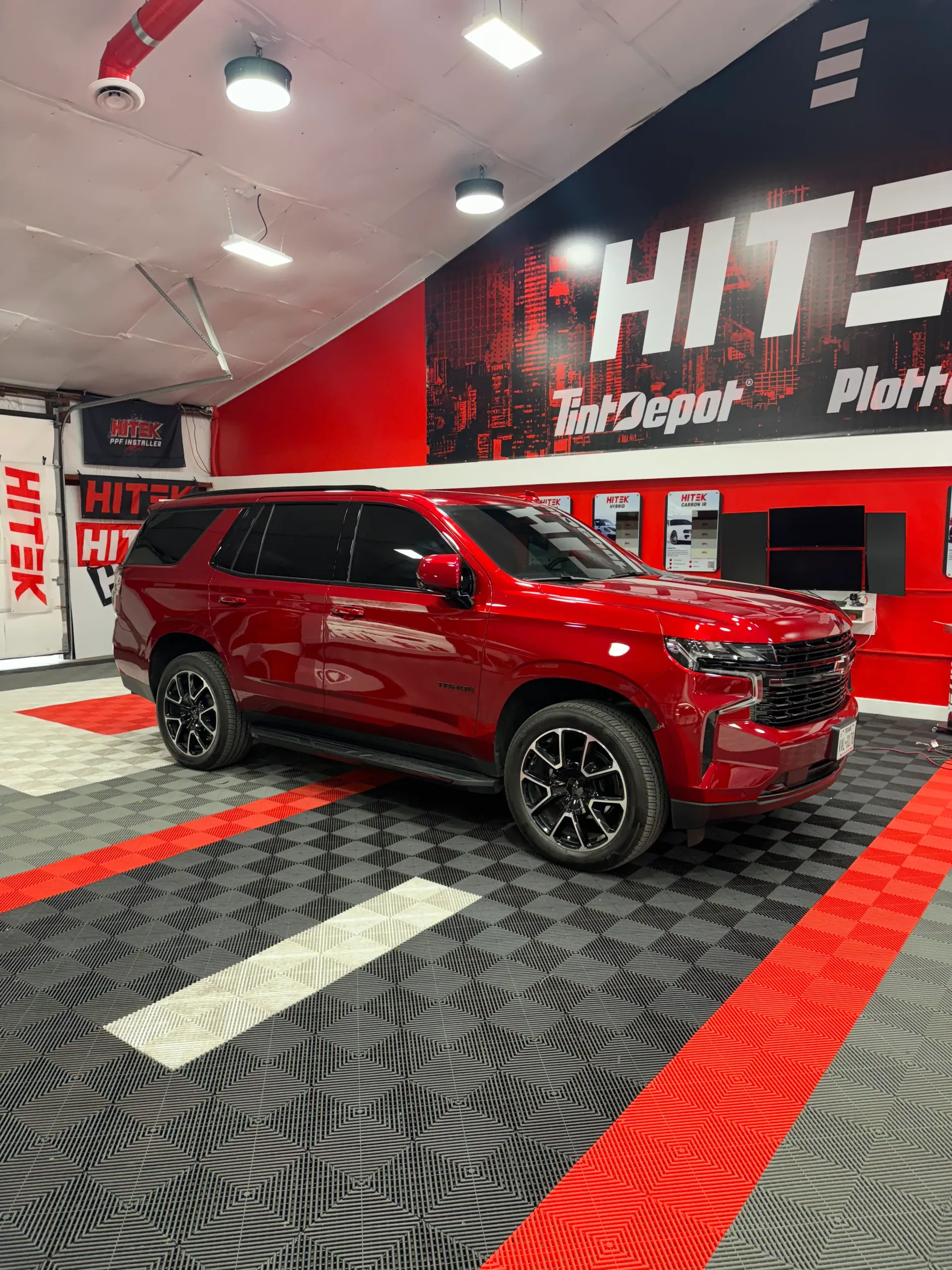 Red Chevy Tahoe SUV in a car depot showroom.