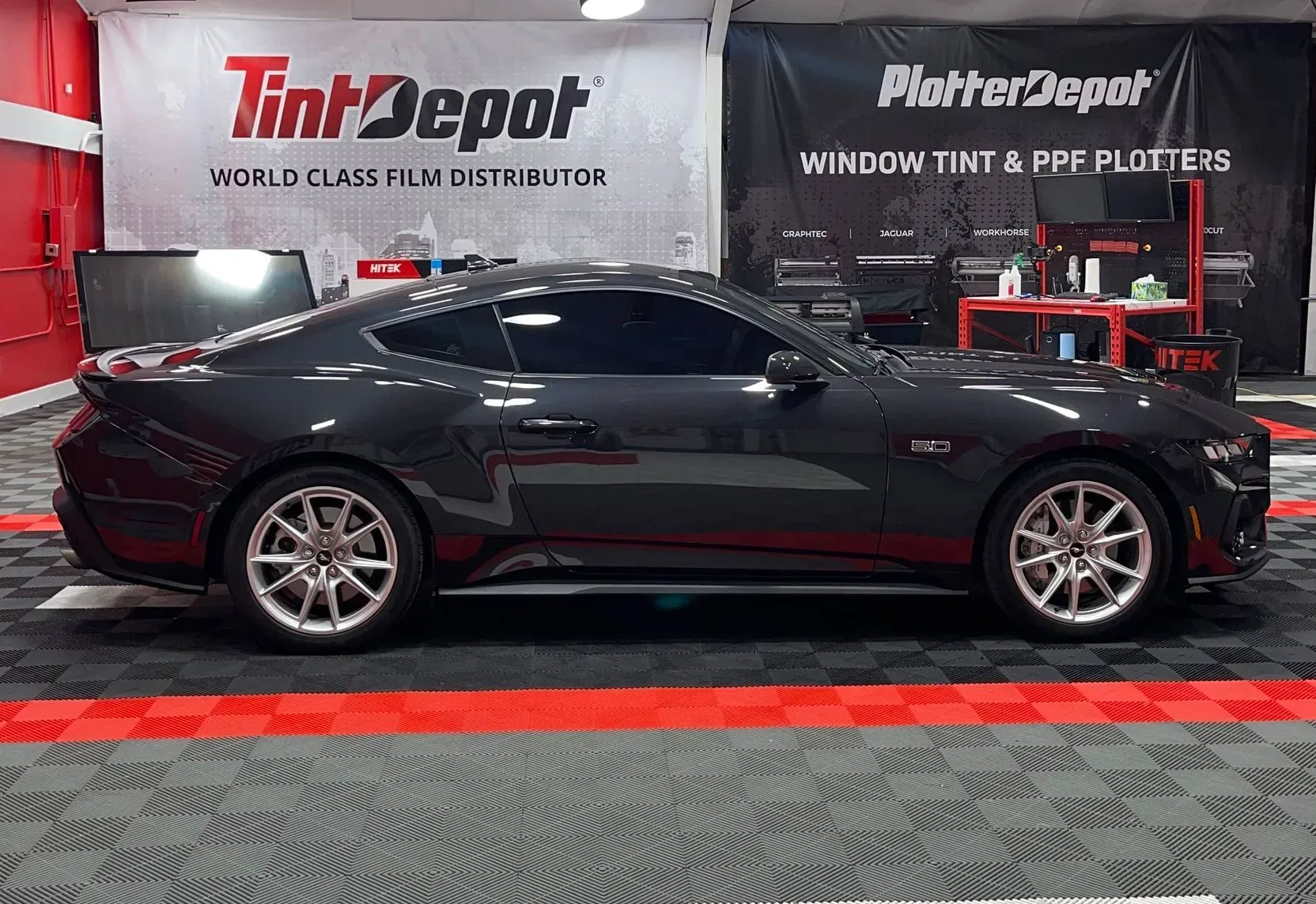 Dark gray sports car with tinted windows in a tint shop.