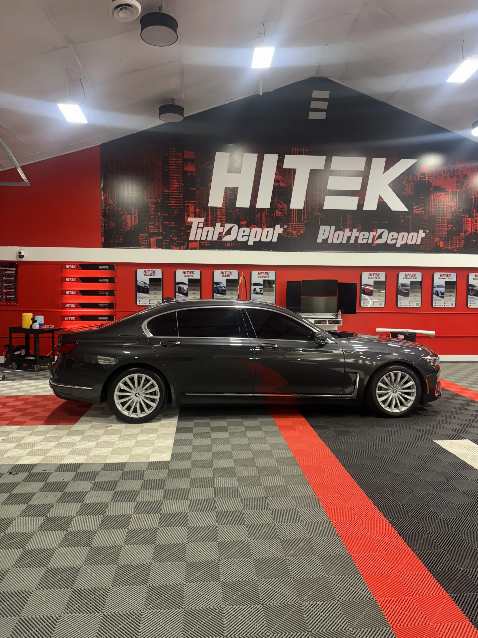 A dark gray BMW sedan parked inside a shop with 