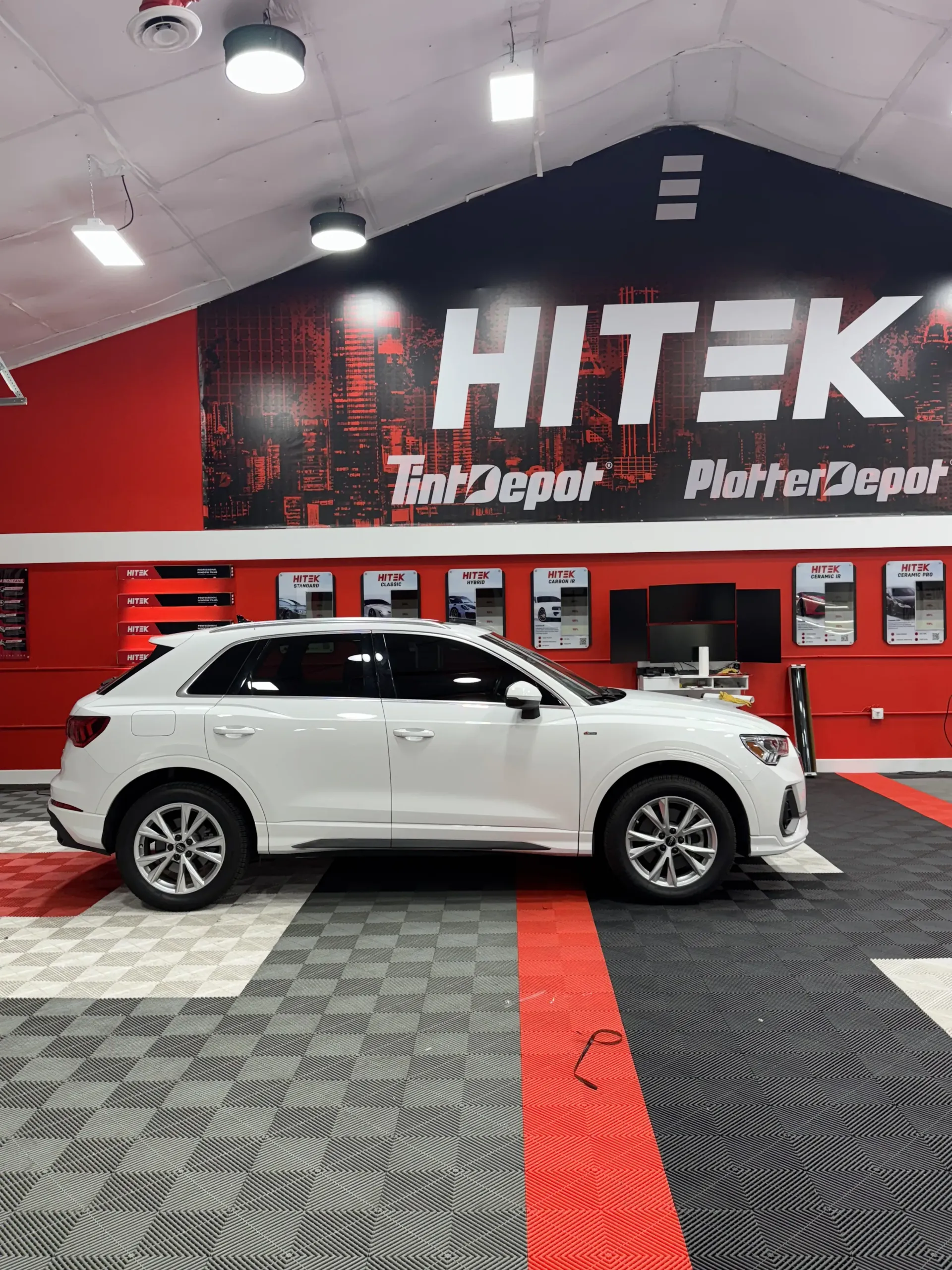 White SUV parked inside a HiTek Tint Depot shop with red and black accents.