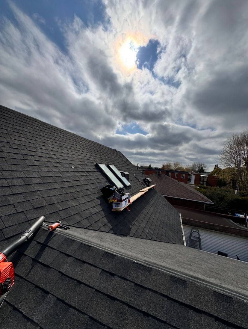 Le soleil brille à travers les nuages au-dessus du toit d'une maison.