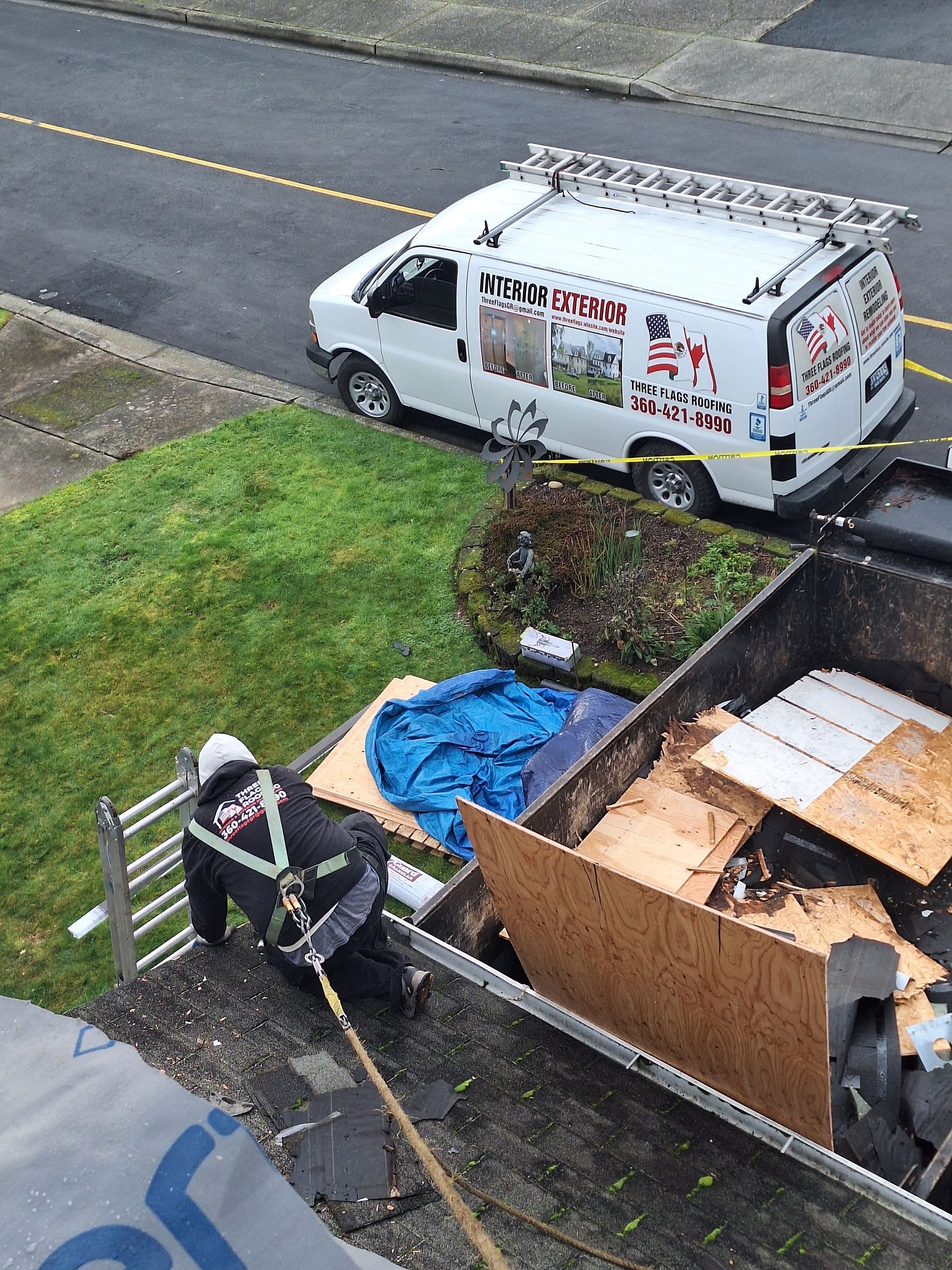Person loading debris into a trailer beside a white van on a residential street.