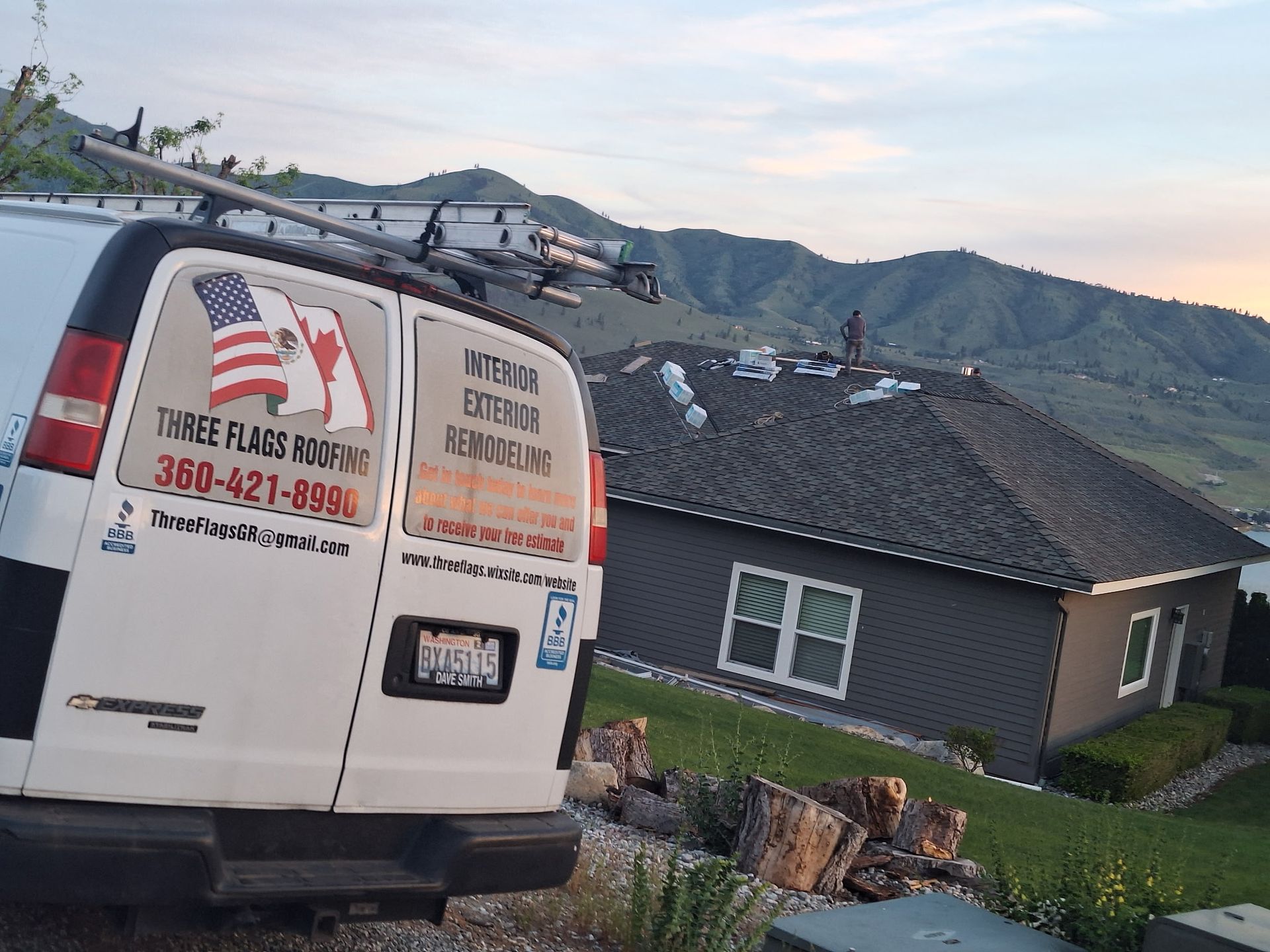 White service van parked beside a sloped-roof house in a hilly neighborhood with mountains in the background