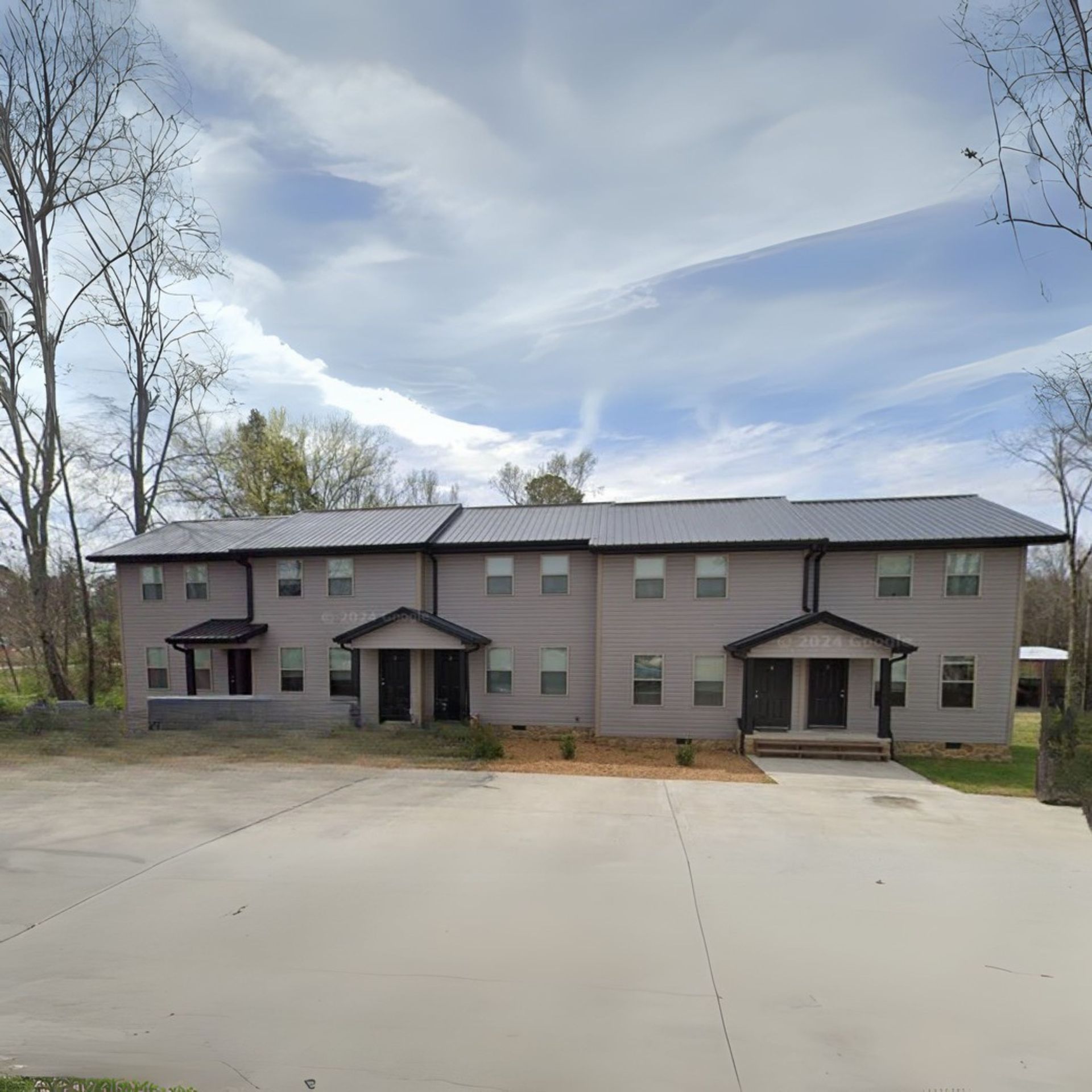 A large apartment building with a lot of windows and trees in the background.