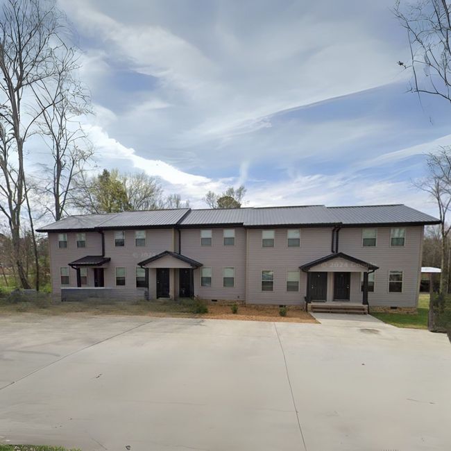 A large apartment building with a lot of windows and trees in the background.