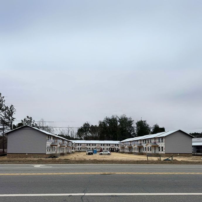 A row of buildings are being built on the side of a road