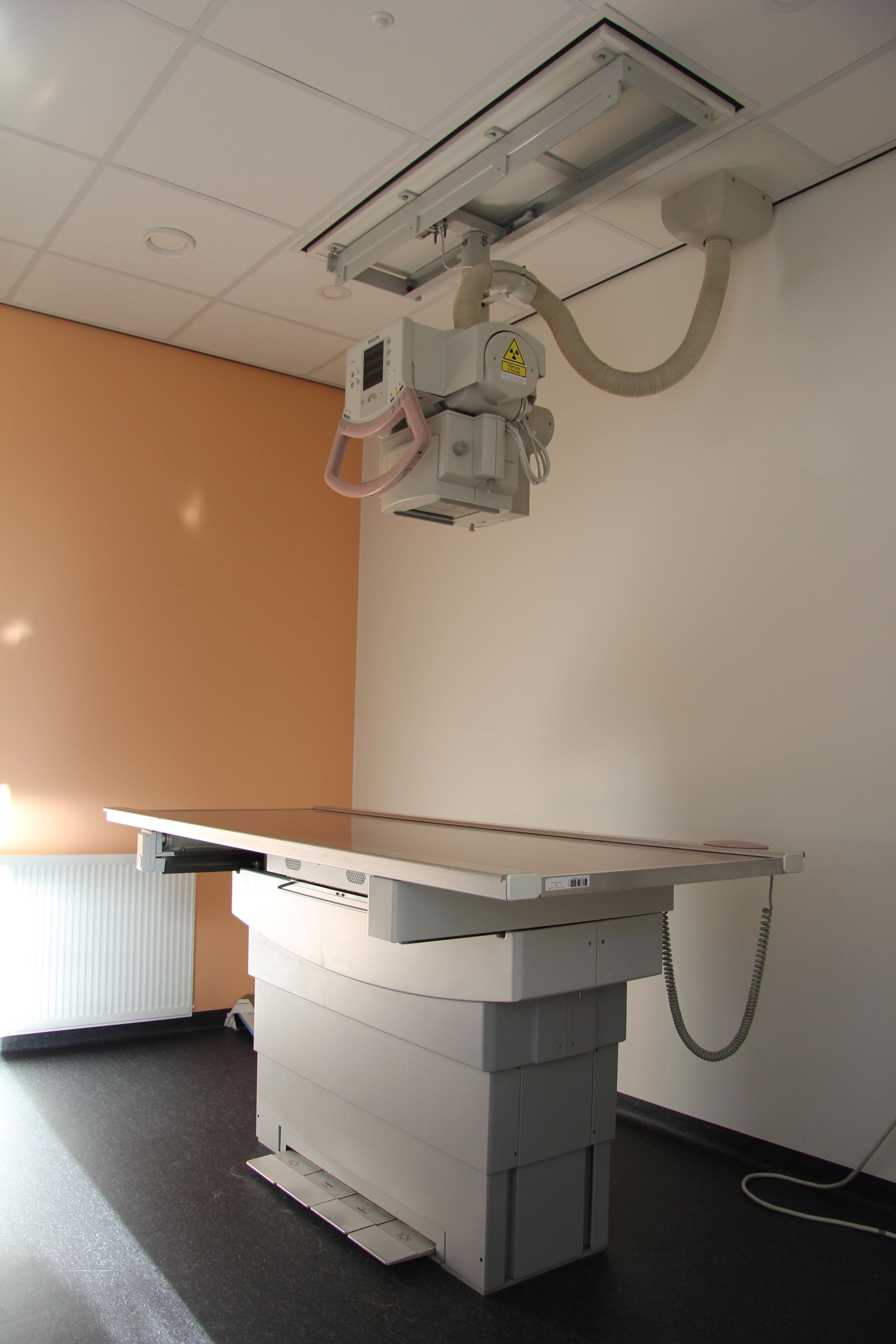 Röntgenkamer met onderzoekstafel en aan het plafond gemonteerd beeldvormingsapparaat
