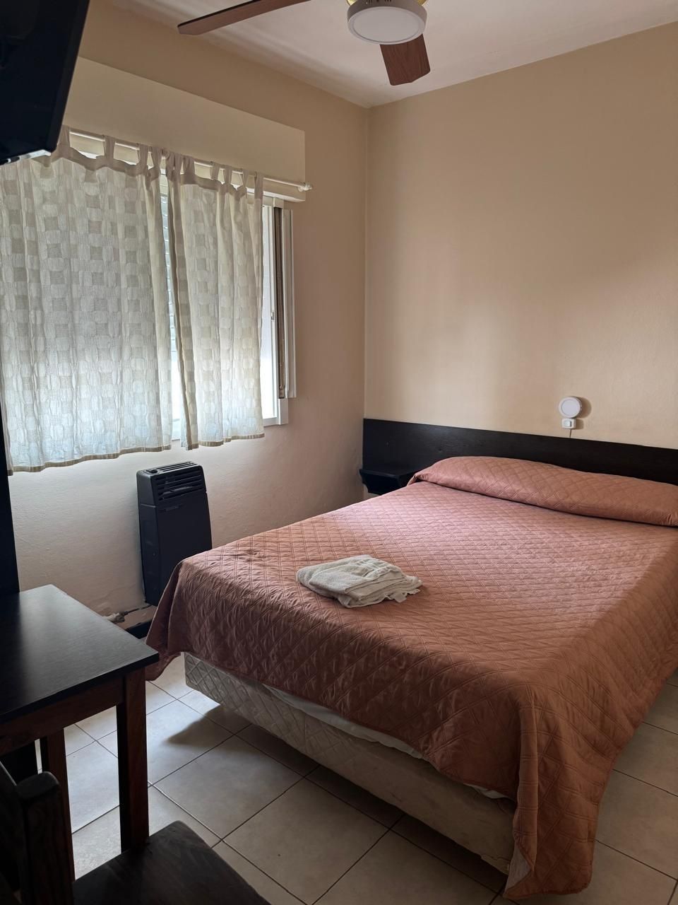 Un dormitorio con una cama que cuenta con una colcha texturizada de color rosa melocotón.