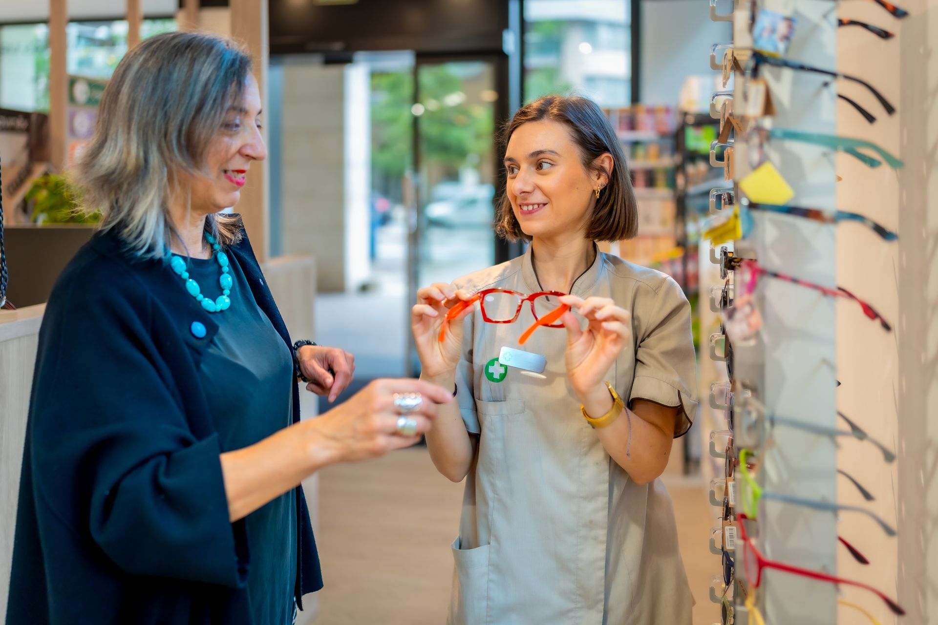 Two people smiling in an eyewear shop, holding colorful eyeglass frames.
