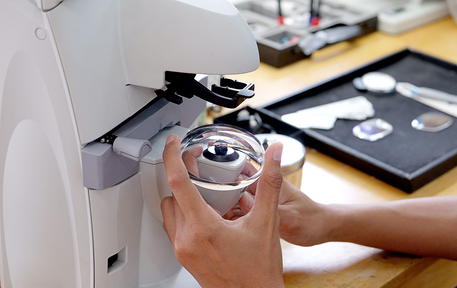 Hands placing a clear bowl under a microscope in a lab