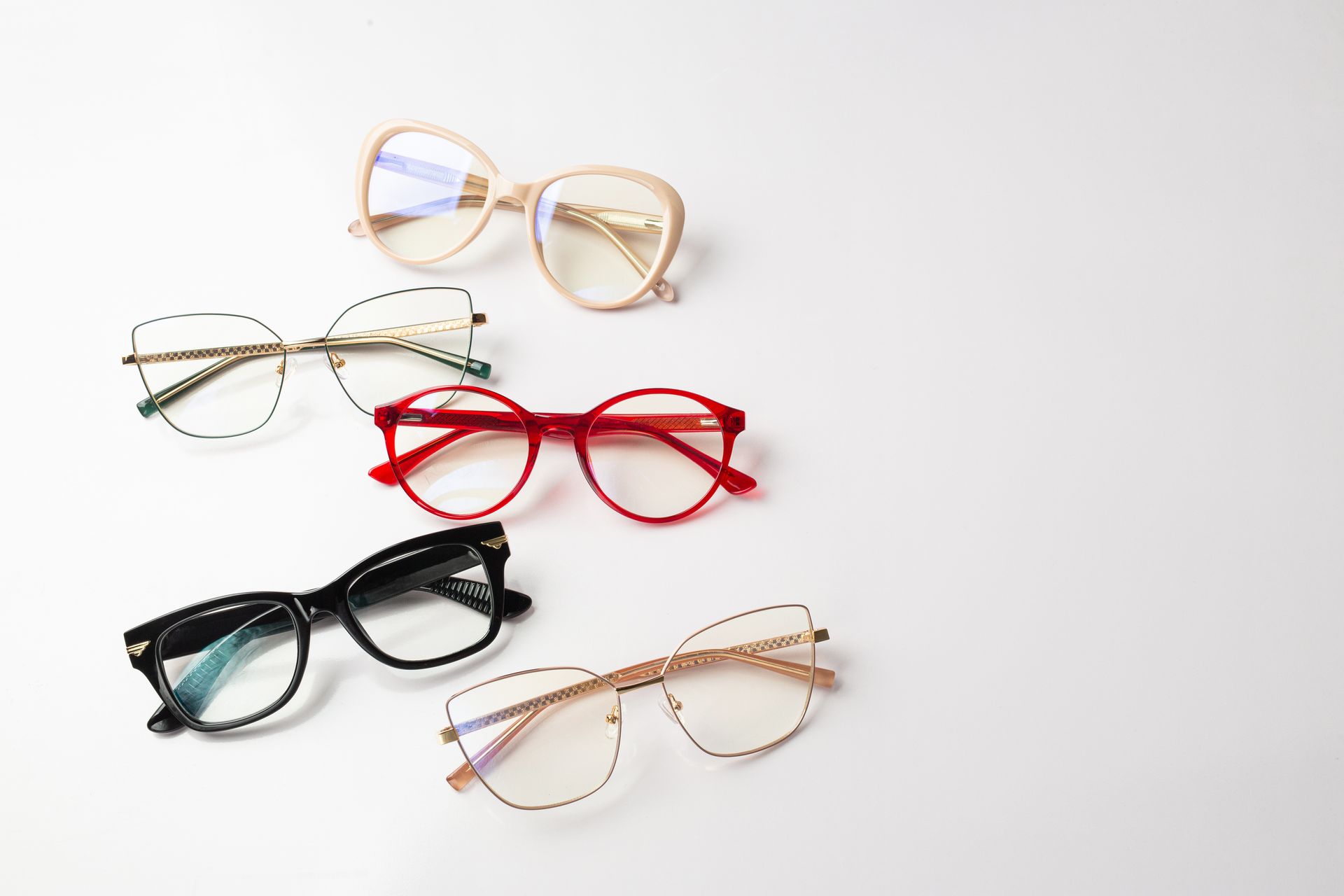 Five pairs of colorful eyeglasses arranged on a light background