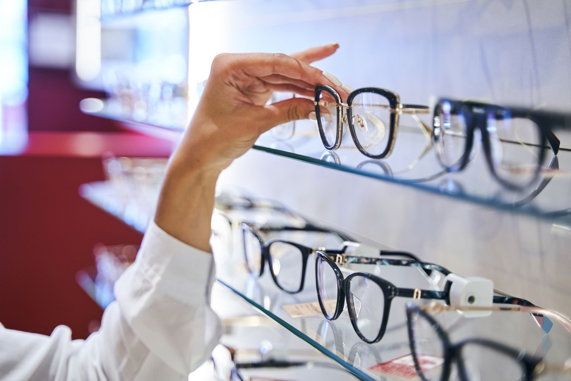 Hand selecting eyeglasses from a display shelf in an optical store