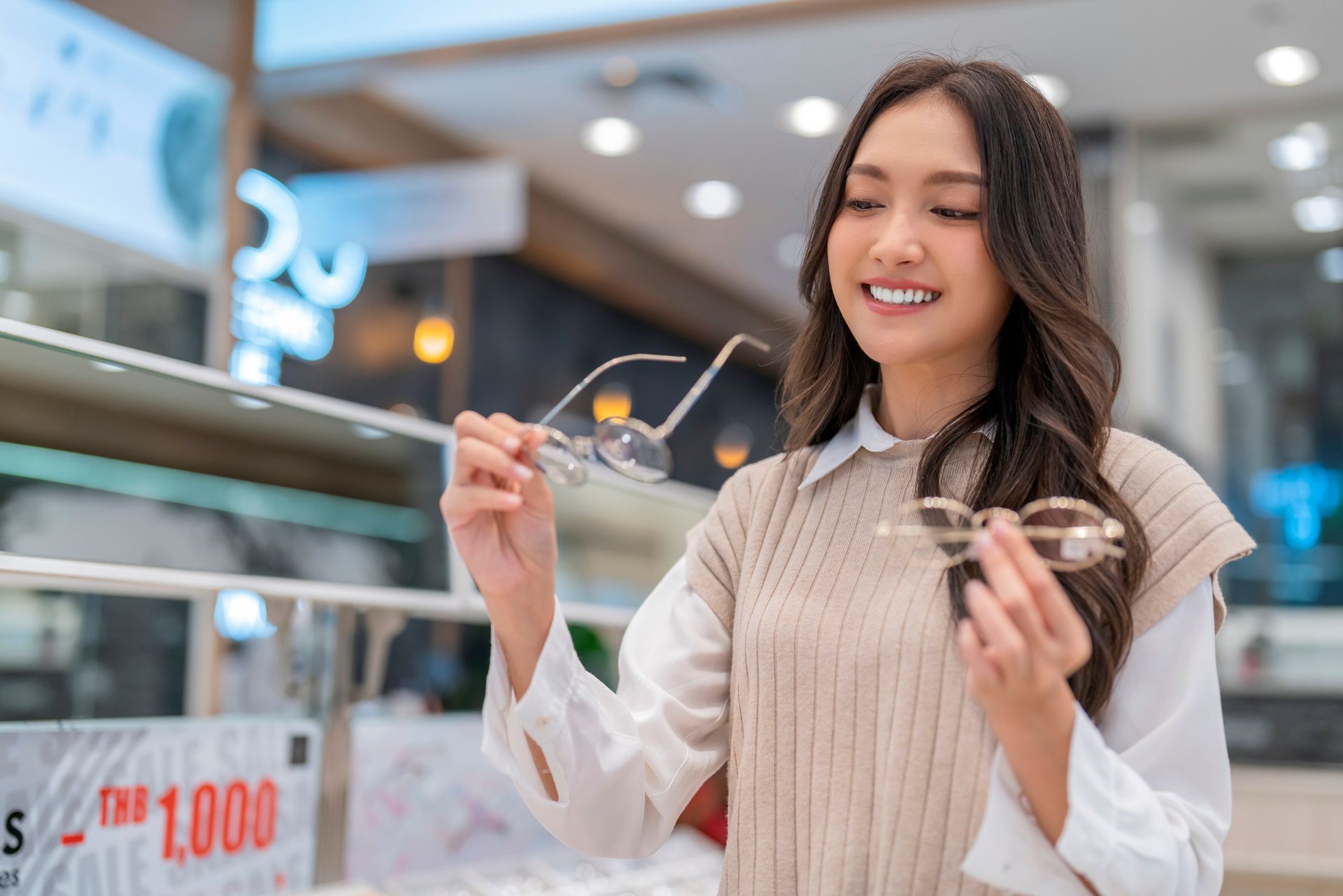 Woman smiling while holding eyeglasses in a bright store display area