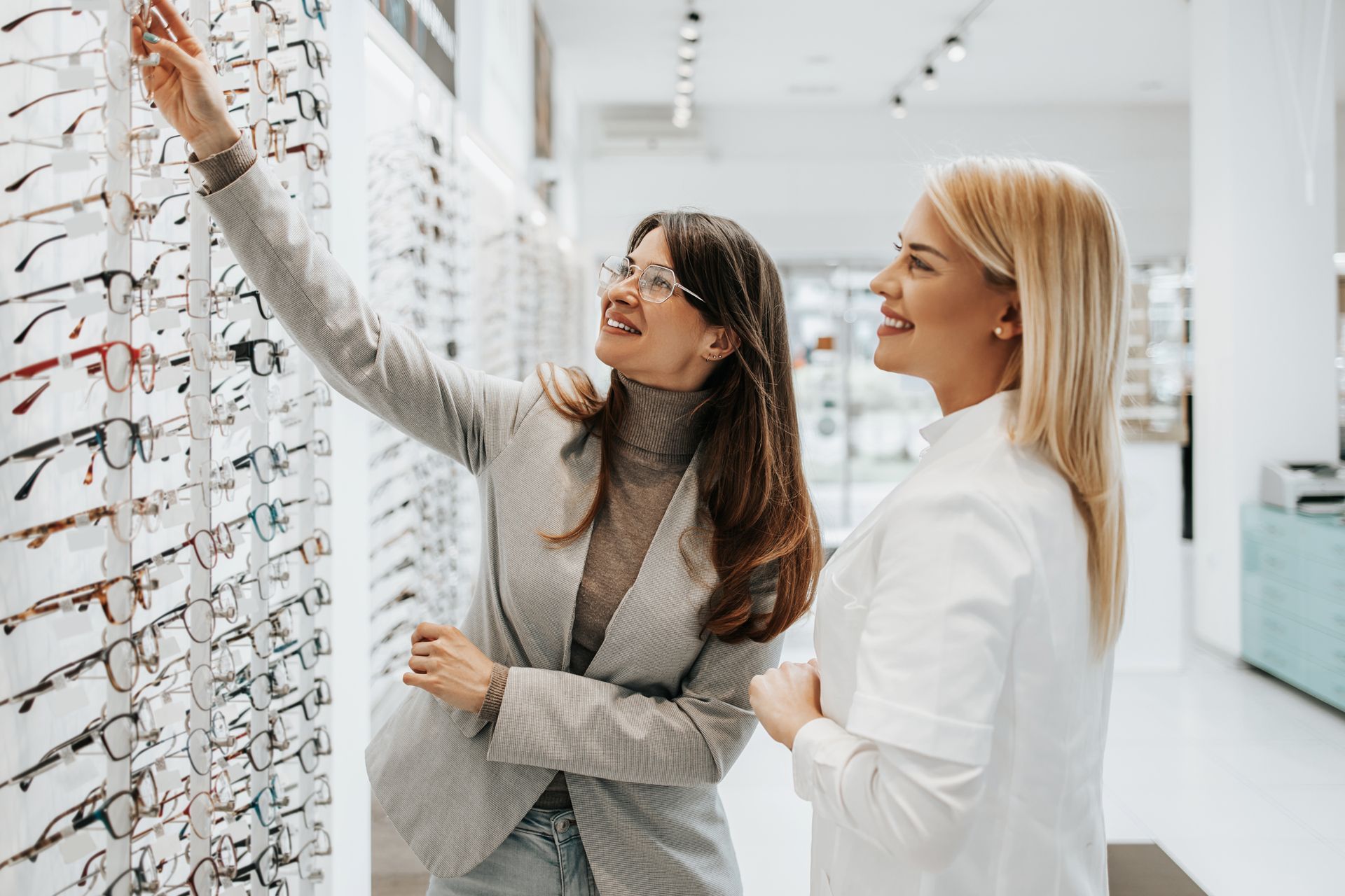 Two women reviewing eyeglass frames in a bright optical store