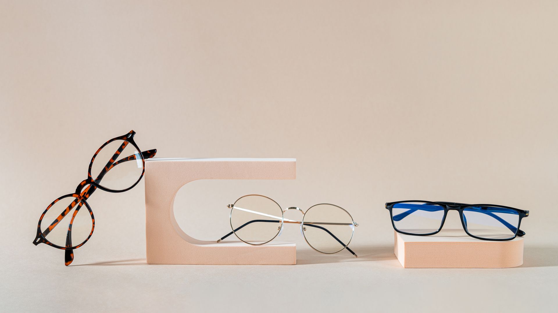Three pairs of eyeglasses in brown, amber, and black on a rustic wooden surface Three pairs of eyeglasses in brown, amber, and black on a rustic wooden surface