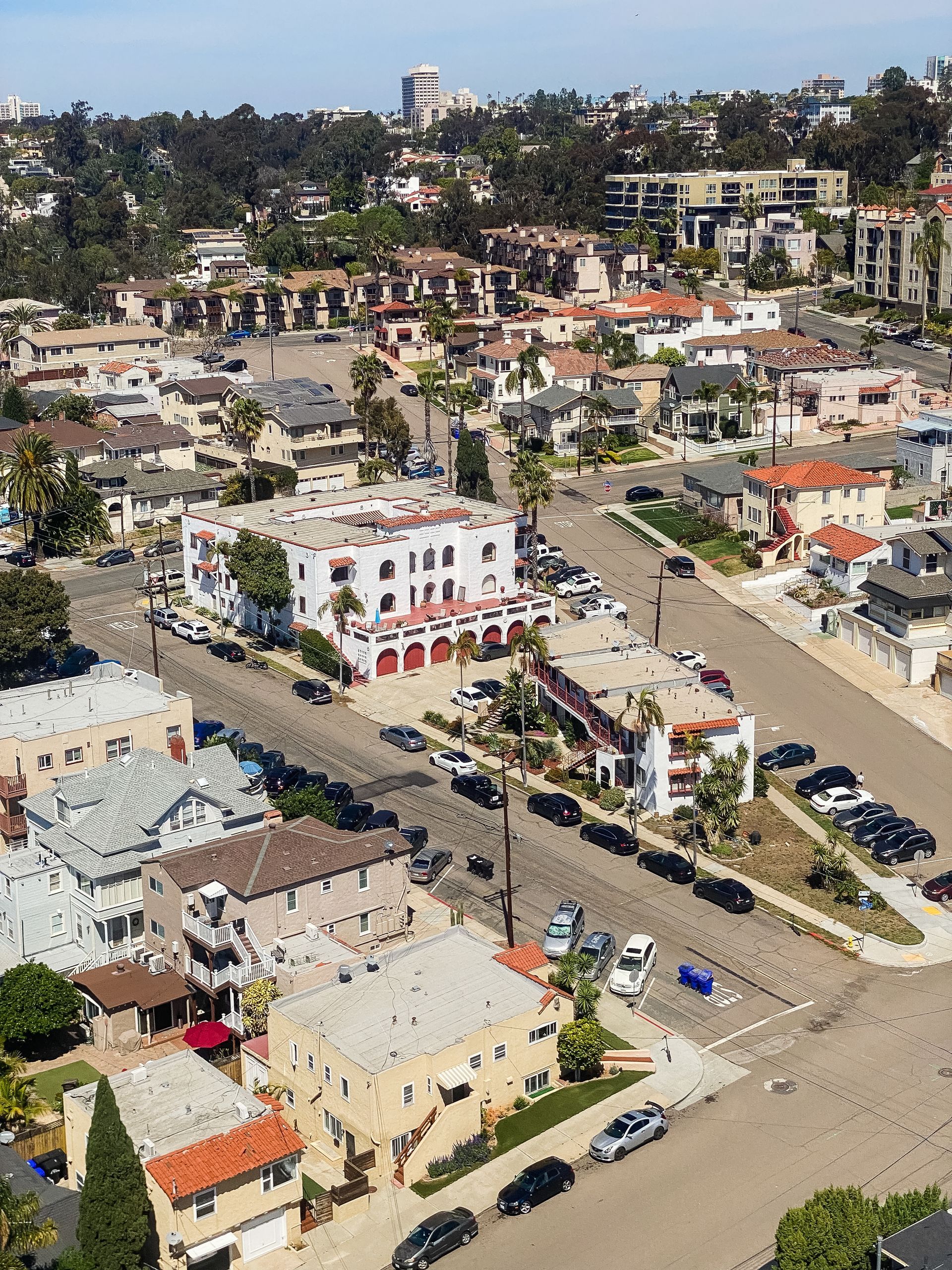 Aerial view of a coastal town with buildings, streets, and cars. A fire station with a red and white facade is visible.