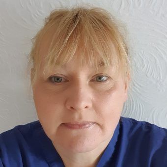 A close up of a woman 's face wearing a blue scrub.