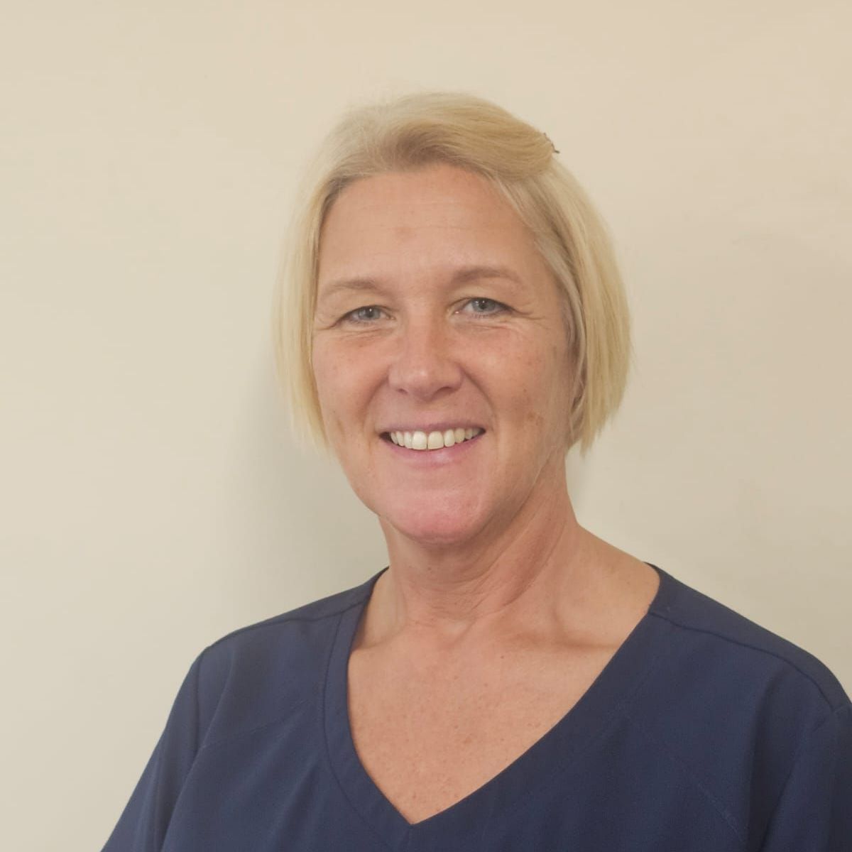 A woman wearing a blue scrub top is smiling for the camera