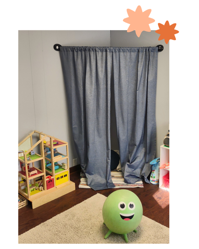 Gray curtains over a window in a child’s room, with a green smiling ball on the floor and a toy dollhouse nearby.