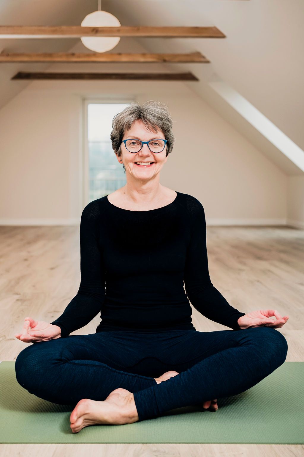 En kvinde sidder i lotusstilling på en yogamåtte.