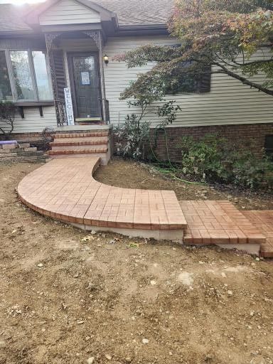 A newly constructed curved brick walkway leading to the front steps and entrance of a house.