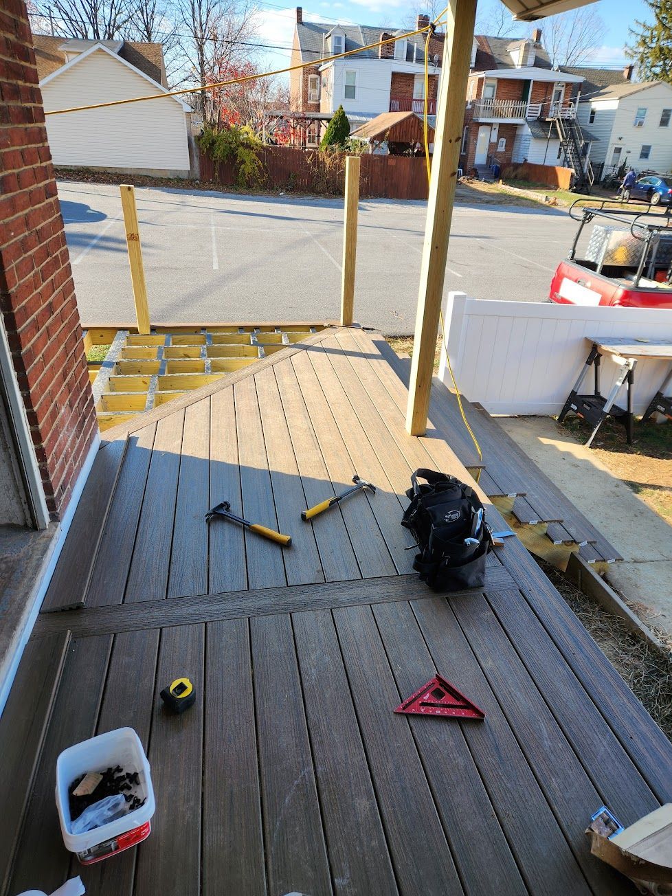 A partially completed wooden deck with tools, a tape measure, and a level scattered on the planks during construction.