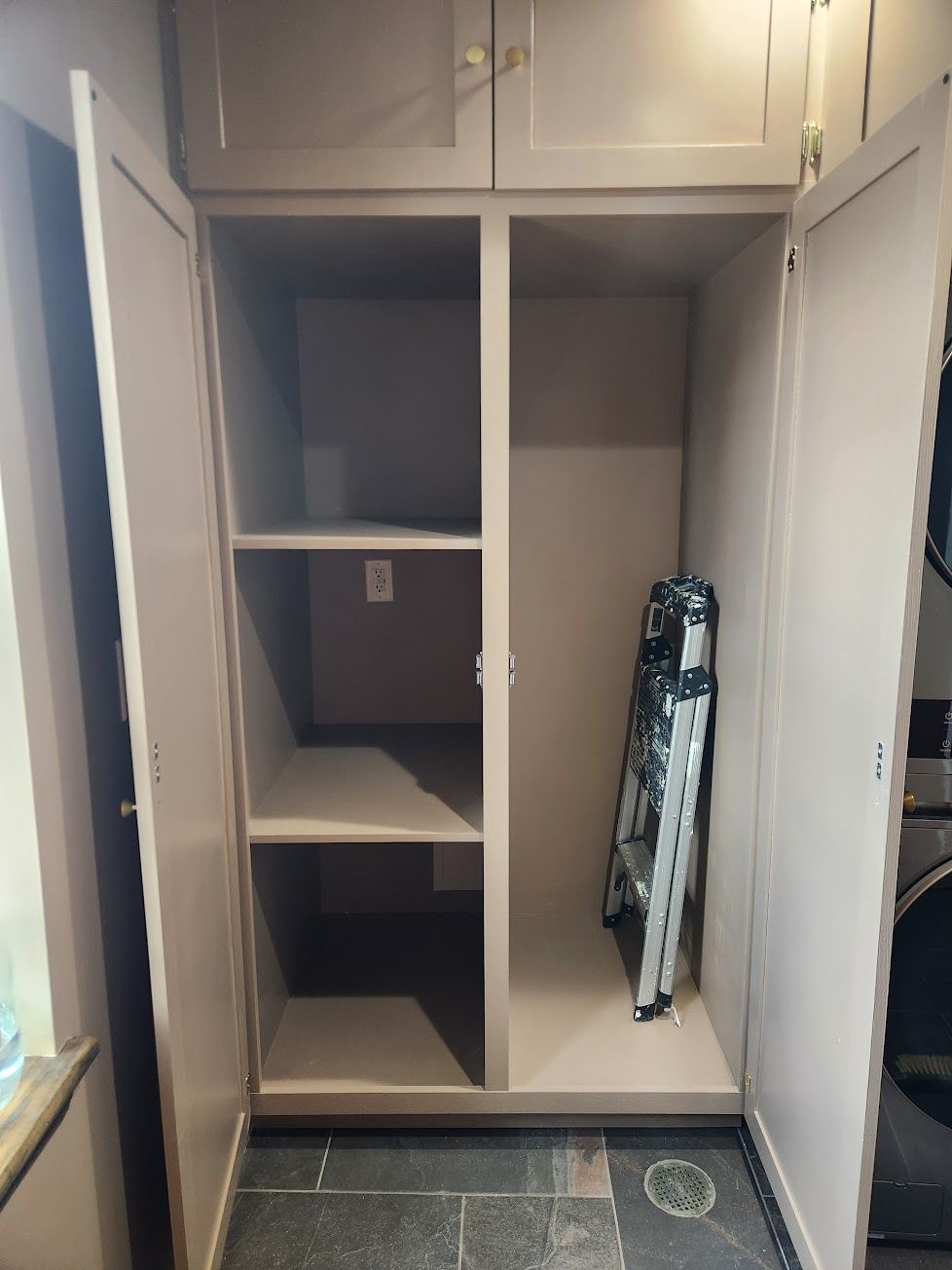 An open, light brown cabinet with a tiered shelving unit on the left and an open storage area on the right.