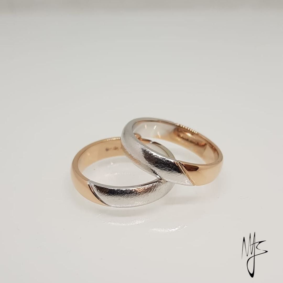 Due fedi nuziali in oro e argento, una sopra l'altra, divise in diagonale.