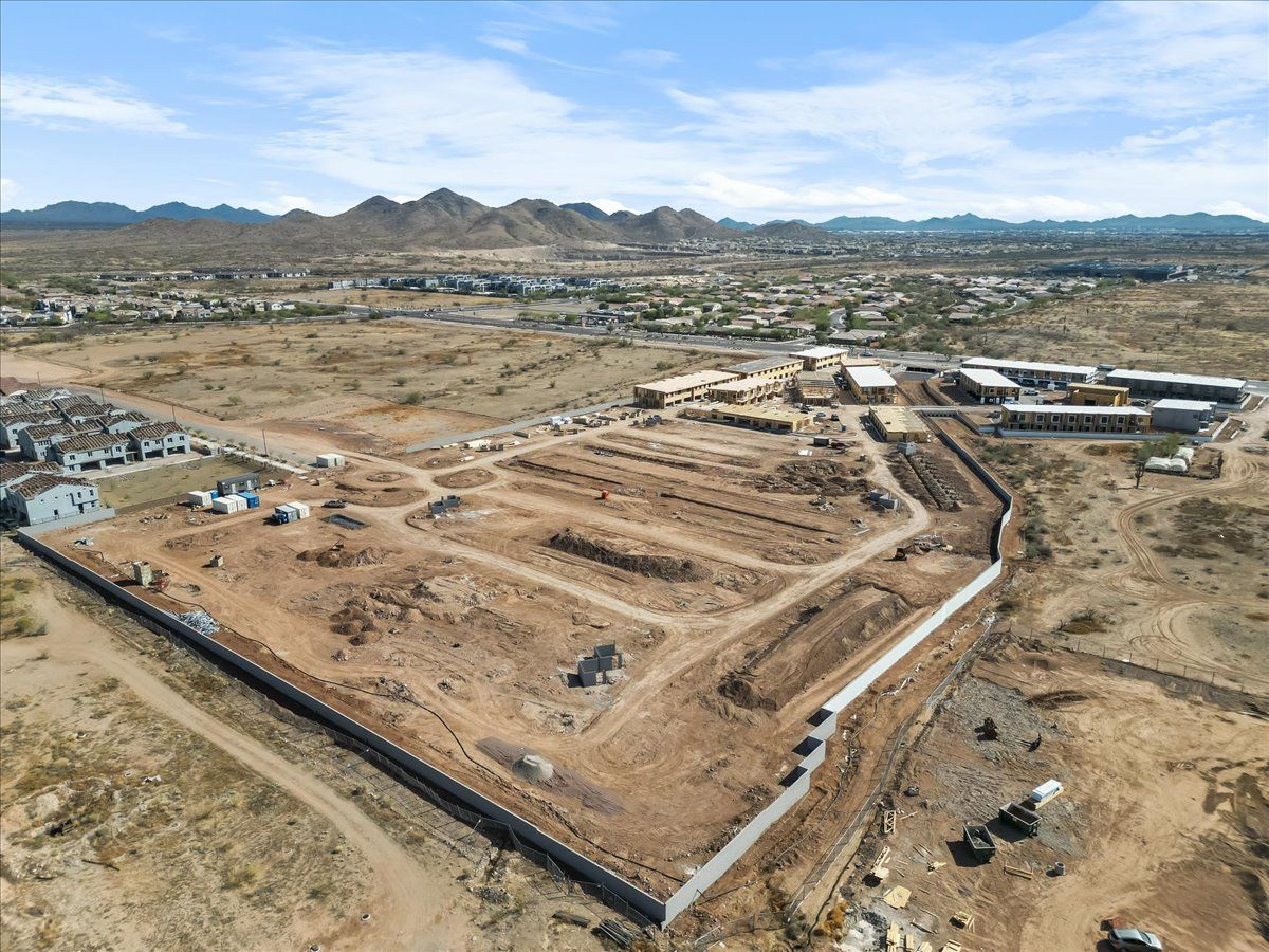 An aerial view of a construction site in the desert with mountains in the background.