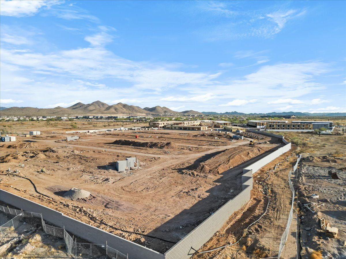 An aerial view of a construction site with a fence and mountains in the background.