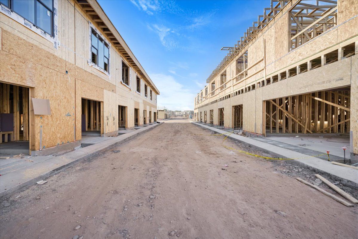 A row of buildings under construction on a dirt road.