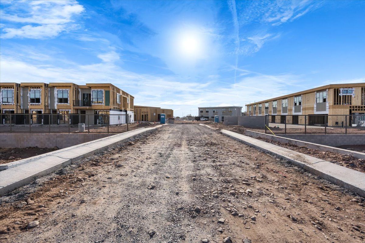 A dirt road leading to a row of houses under construction.