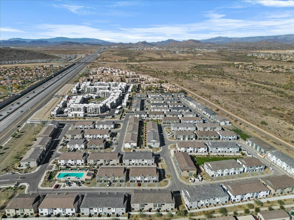 An aerial view of a residential area with a highway and mountains in the background.