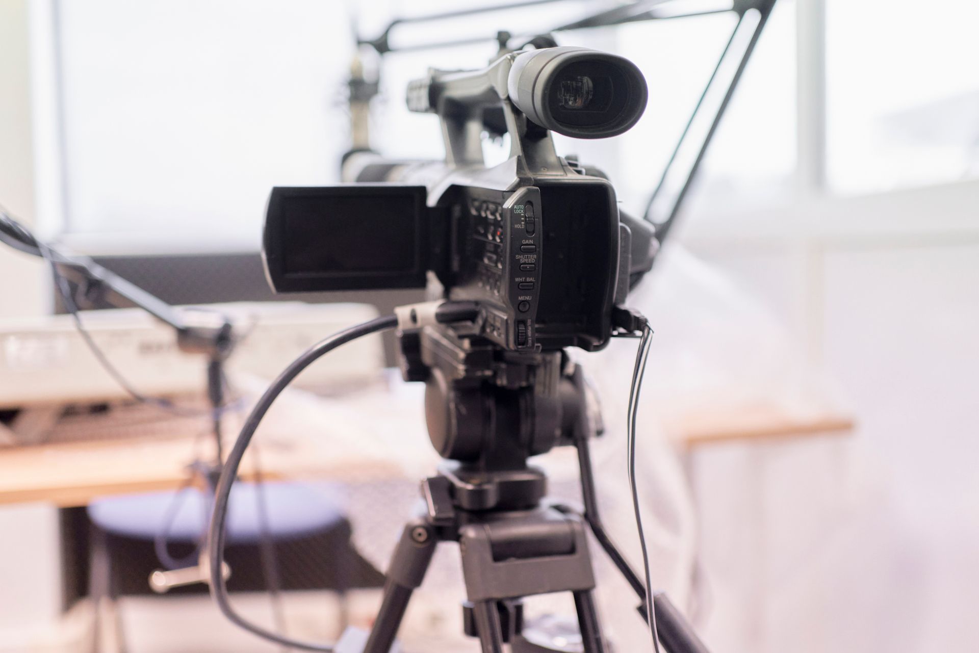 A video camera is sitting on a tripod in a room.